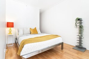 A bedroom area with a queen sized bed & a privacy screen.