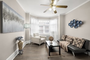 Living room features flat screen TV, sofa sleeper, cozy chair, and serene ambiance.