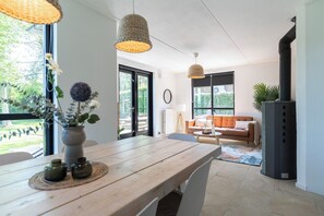 Open-plan space with a rustic dining table, cozy lounge corner, and lots of natural light—ideal for relaxed meals and quality time.