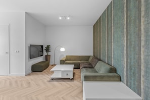 Living space with green modular seating, a white coffee table, and stylish accent wallpaper creating a cozy and contemporary vibe.