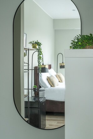 This creative mirror reflection beautifully captures the cozy and stylish design of the bedroom, showcasing the inviting bed with decorative cushions and ambient lighting, complemented by a touch of greenery.