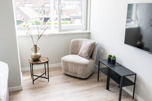 Inviting nook by the window featuring a plush armchair and a sleek side table, ideal for reading or enjoying the city view.