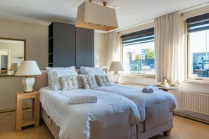 Bright and inviting bedroom with twin beds, plush pillows, and large windows allowing natural light to create a cozy, serene ambiance.