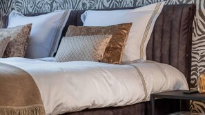 A stylish bedroom featuring a velvet bed, zebra-print wallpaper, large windows with lush views, warm lighting, and elegant furniture for a sophisticated ambiance.