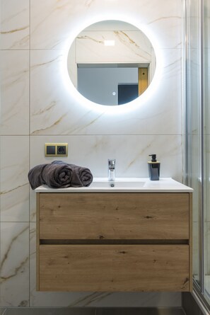 A sleek bathroom with a circular LED-lit mirror, marble walls, a modern wooden vanity, neatly rolled towels, and a stylish soap dispenser for a luxurious touch.

Zak weg in comfort bij Bed en Koffie in Hotel Centrum Tilburg—een knusse kamer met toegang tot de keuken, perfect voor een goedkope overnachting bij de Efteling of Poppodium 013.