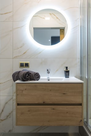 A sleek bathroom with a circular LED-lit mirror, marble walls, a modern wooden vanity, neatly rolled towels, and a stylish soap dispenser for a luxurious touch.
Zak weg in comfort bij Bed en Koffie in Hotel Centrum Tilburg—een knusse kamer met toegang tot de keuken, perfect voor een goedkope overnachting bij de Efteling of Poppodium 013.