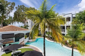 Enjoy cooling off in the large refreshing shared pool. The pool is surrounded by green palm trees and sun loungers. 
