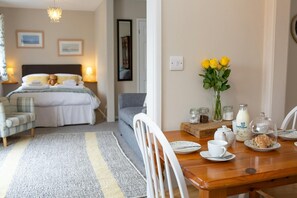 dining table dressed for dinner leading to bedroom/lounge area with large grey and yellow rug