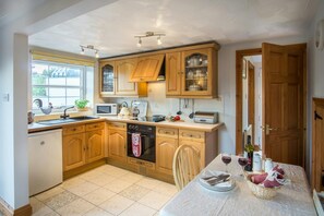 Fitted kitchen with cooker, dining table and chairs