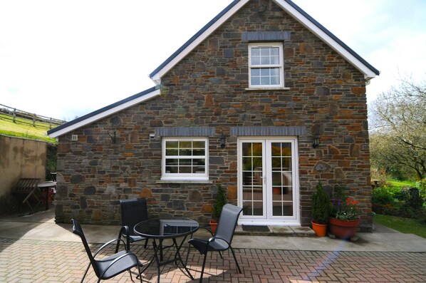 exterior image of cottage, patio area with outdoor seating