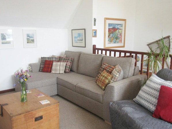 Living area with sofa, armchair, coffee table and flowers