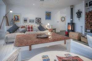 Large cream fabric sofa with red and grey cushions. Various prints on the walls