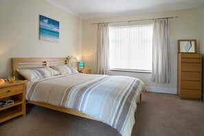 Bedroom with bed, bedside units and lamps, chest of drawers