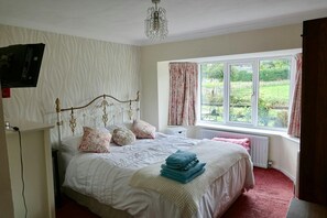 King size bed, chest of drawers, bedside table and towels folded on the end of the bed