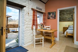 Dining table and 2 chairs by a window, door open to garden