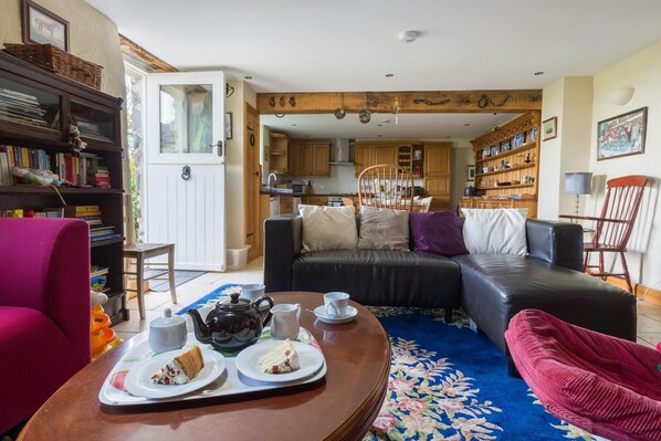 The Stables sitting area with leather sofa , coffee table, red armchairs and book shelves
