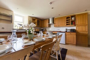 The Stables kitchen/dining area with pine table set for 8, wood kitchen cupboards and dishwasher
