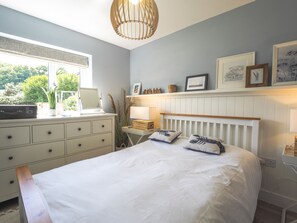 Bedroom with double bed, clothes dresser and bedside table.