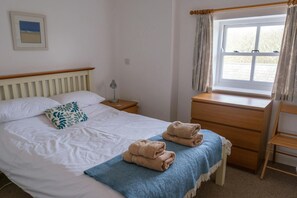 Bedroom with double bed, chest of drawers, bedside table and lamp