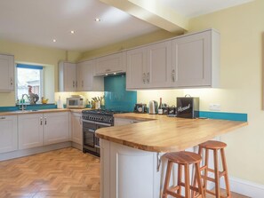 Kitchen and breakfast bar with two stools, cooker, sink, window