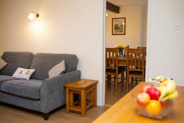 Large sofa with a nest of table and door leaving to the dining room