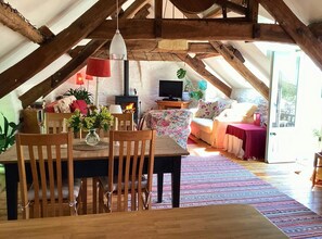 Open kitchen with dining room to seat 4 with flowers at the centrepiece , living room behind
