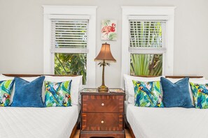 Welcome to the expansive second bedroom upstairs, where spaciousness meets comfort. Two inviting wooden platform full beds rest upon cedar wood floors, bathed in natural light streaming through ample windows.