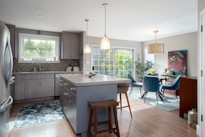 Speaking of the kitchen, here's a closer shot. It has an island, bright surfaces, modern appliances, and all the kitchenware you would ever need! In the background you'll see the dining area.