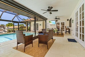 Conversation set on lanai with TV in the background and bluetooth speakers