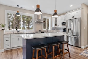 Experience culinary delight in our well-stocked kitchen, complete with a spacious countertop and stools, inviting you to gather, create, and savor delicious meals with ease and convenience.