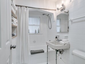 The compact bathroom has a tub/shower combo. 