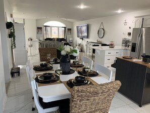 Open concept living room and kitchen with 85 inch tv 2 couches. 