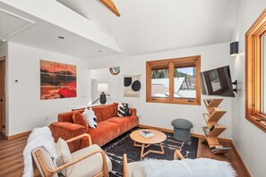 The open-concept living/dining room with large windows framing your riverside oasis
