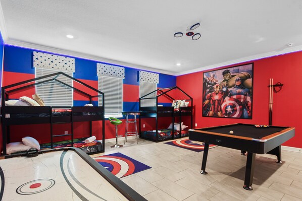 Experience a superhero-themed game room with bunk beds, pool, and air hockey
