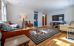 Living room with abundant natural light, original hardwood floors and large smart tv