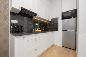 A sleek kitchen with white cabinetry, a black backsplash, and modern appliances for a chic, functional design.

