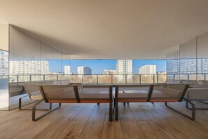A spacious balcony with a large dining table and a stunning panoramic view of the city skyline.

