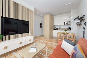 A modern living room with a wall-mounted flat-screen TV, built-in cabinetry, and a sofa facing a minimalist coffee table.