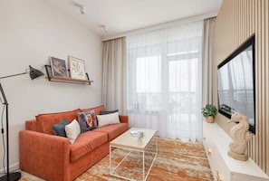 The same lounge corner from a different angle, highlighting the sofa’s textured cushions and a floor lamp beside it.