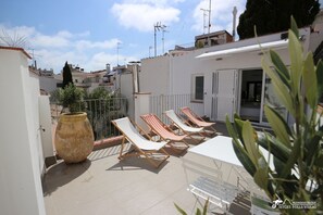 Dachterrasse mit Sonnenliegen und schickem Essbereich.