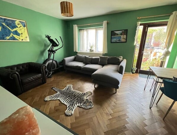 The living room offers a large corner sofa, dining table and 50 inch TV.