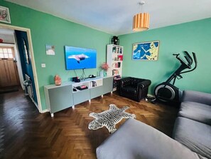 The living room offers a large corner sofa, dining table and 50 inch TV