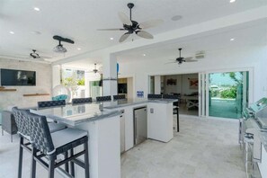 Outdoor kitchen with gas grill, wet bar, ice maker and mini refrigerators.