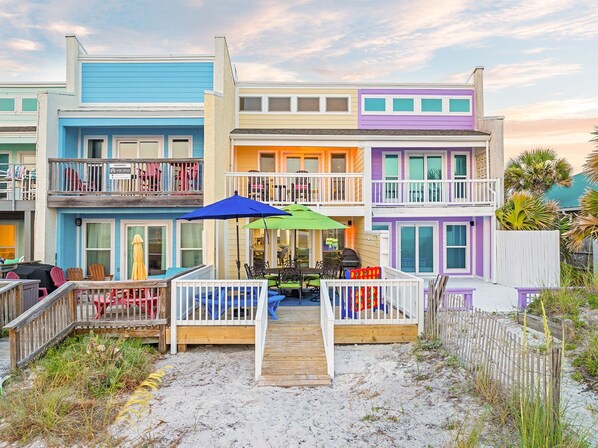 Welcome to Sunset Sandbox! Relax in style at this beautifully designed beachfront townhouse. With its colorful exterior and spacious outdoor seating areas, it's the perfect place to unwind and enjoy the stunning sunset views over the ocean.