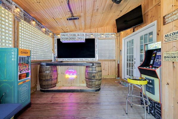 Ultimate entertainment: Patio bar featuring a Pac-Man game and TV, creating a fun and lively atmosphere or outdoor gatherings.