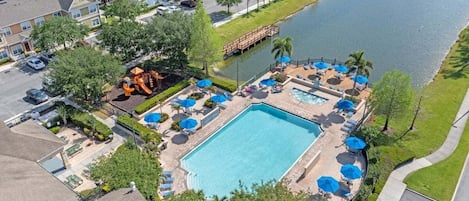 Immerse yourself in tranquility as you gaze upon the serene poolside oasis from a bird's eye view, where sparkling waters meet lush greenery under the warm embrace of the sun.