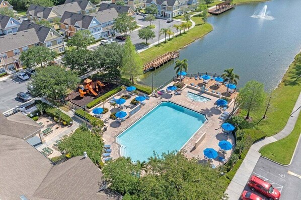 Immerse yourself in tranquility as you gaze upon the serene poolside oasis from a bird's eye view, where sparkling waters meet lush greenery under the warm embrace of the sun.