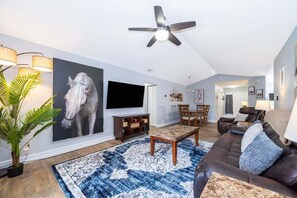 Step into the spacious living area adorned with a grand painting hanging prominently on the wall, while sinking your feet into the plush carpeting beneath.