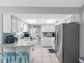The open layout of the kitchen allows you to stay connected with your guests in the adjacent living and dining areas while enjoying the serene ambiance of the poolside scenery.