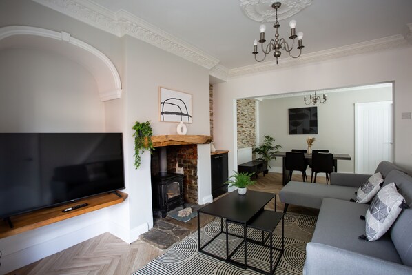 Elegant living and dining space with a cozy fireplace, modern furnishings, and a large TV. Stylish, spacious, and inviting.